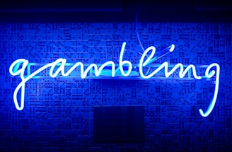 A bright blue neon sign spells out the word 'gambling' in cursive script. The background features a textured wall covered in domino tiles, also illuminated by the blue light, creating a vivid and visually striking scene.
